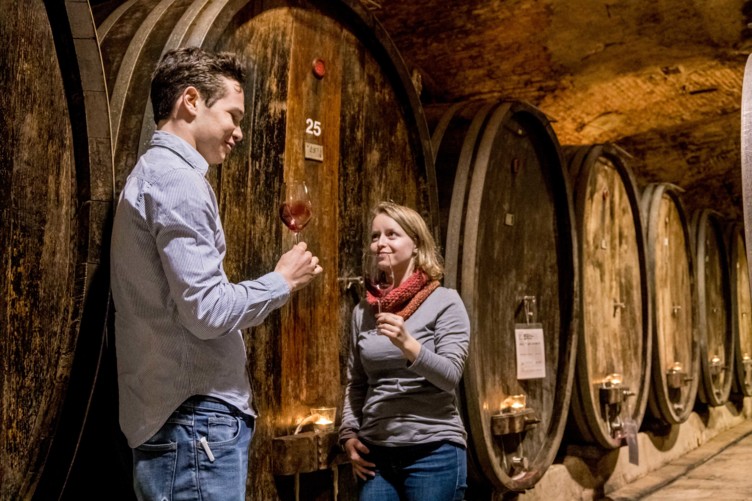 Frau und Mann probieren Wein vor großen Weinfässern